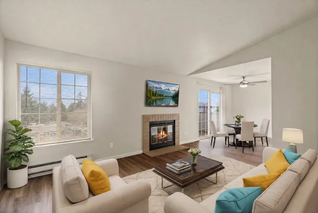 Bright and cozy living room with a warm fireplace, elegant dining area, and large windows offering scenic views.
