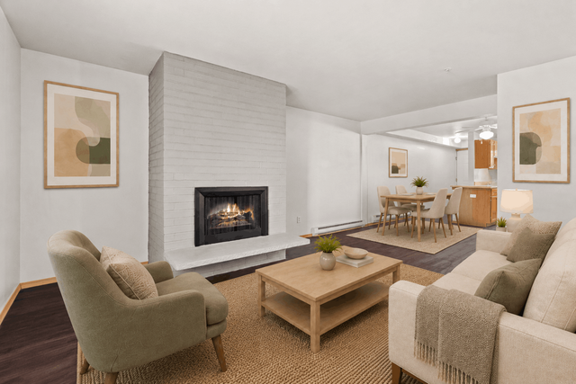 Inviting living room with a cozy fireplace, modern furniture, and a sleek dining area leading to a contemporary kitchen.