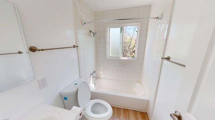 Bright and airy bathroom with elegant fixtures, white tile walls, and a window allowing natural light.