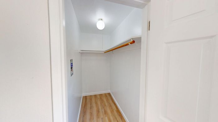 Bright and spacious walk-in closet featuring elegant wooden flooring and modern lighting.