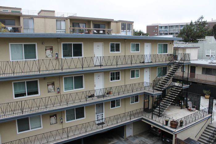 Charming multi-story apartment building with spacious balconies, excellent natural lighting, and outdoor sitting area.