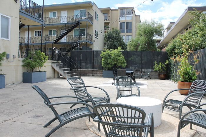 Charming apartment complex courtyard featuring stylish outdoor seating, lush greenery, and modern architectural design.