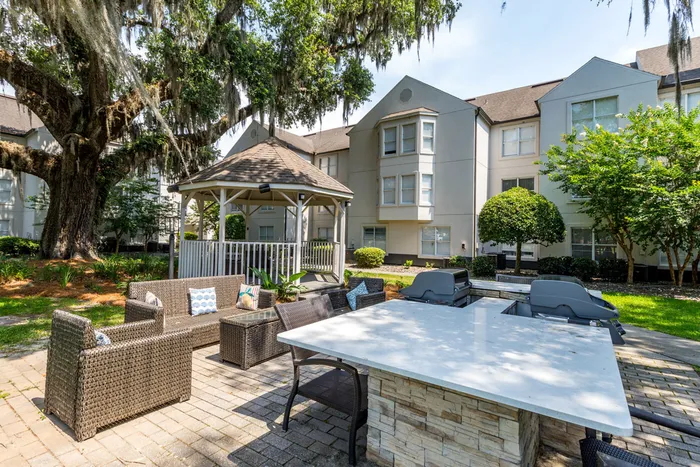 grilling area with grills and seating outside apartment building on sunny day