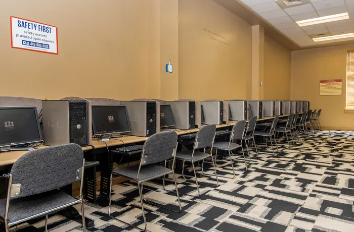 Modern computer lab with rows of Dell desktops and stylish seating on a geometric carpet.