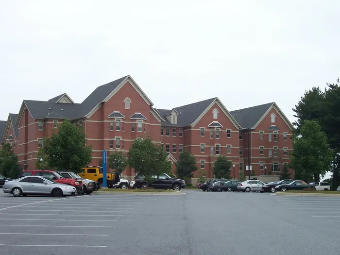 Elegant red brick apartment buildings with gabled roofs and ample parking.