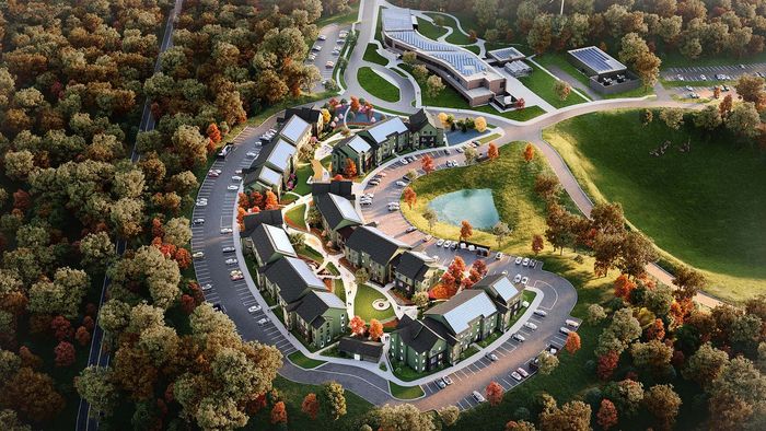 Aerial view of a picturesque residential complex nestled among lush greenery, featuring modern townhouses with solar panels and scenic pathways encircling a tranquil pond.