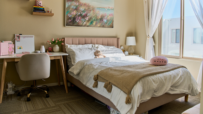 Bright and cozy bedroom with soft bed, charming desk area, and a large window letting in natural light.