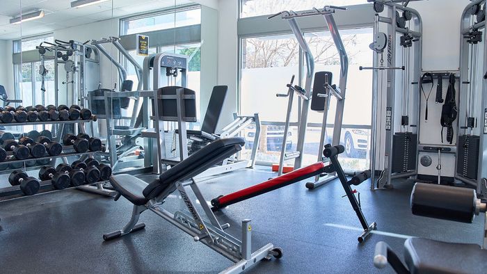 Modern fitness center with state-of-the-art equipment, including free weights and exercise machines, spacious and bright with large windows.