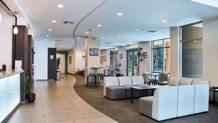 Inviting apartment lobby with modern seating, stylish lighting, and large windows offering natural light.
