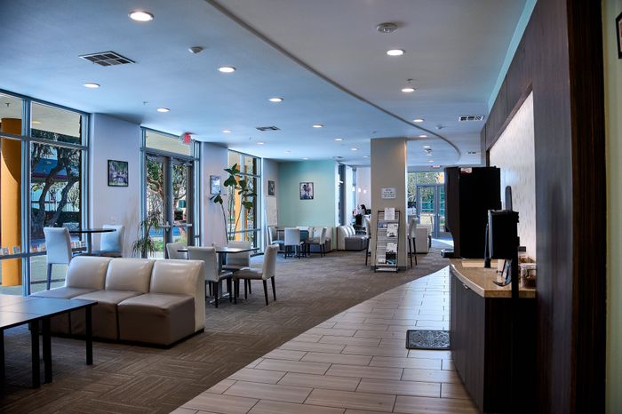 Modern lounge area in an upscale apartment complex featuring sleek seating, natural lighting from large windows, and contemporary decor.