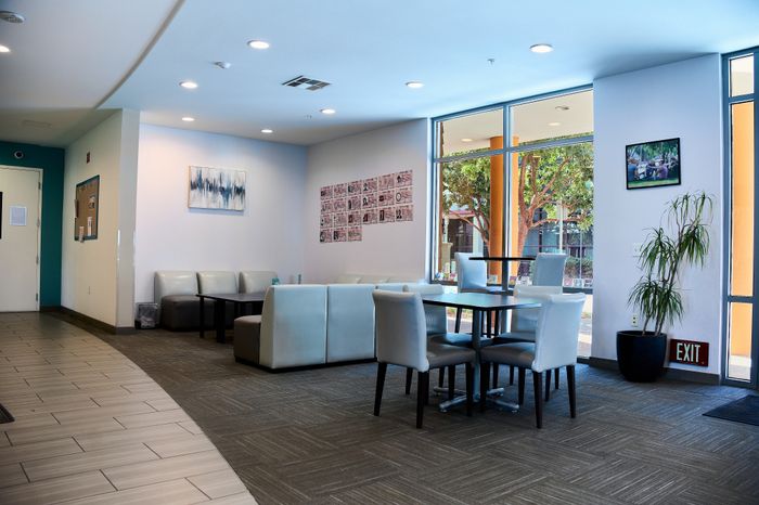 Modern apartment common area with stylish seating, large windows, and vibrant wall art, creating a bright and inviting atmosphere.