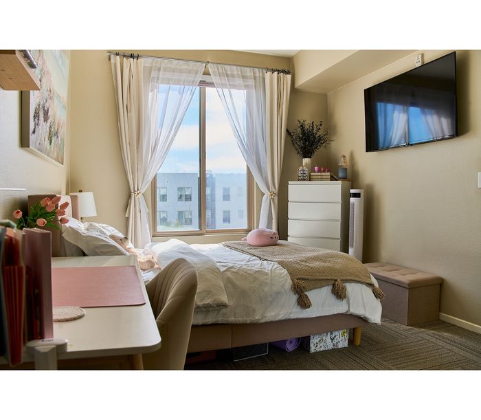 Bright and cozy bedroom featuring elegant curtains, plush bedding, and modern decor, with a scenic view through the window.