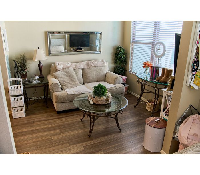 Bright and cozy living room featuring a plush sofa, elegant glass coffee table, and stylish decor elements with abundant natural light.