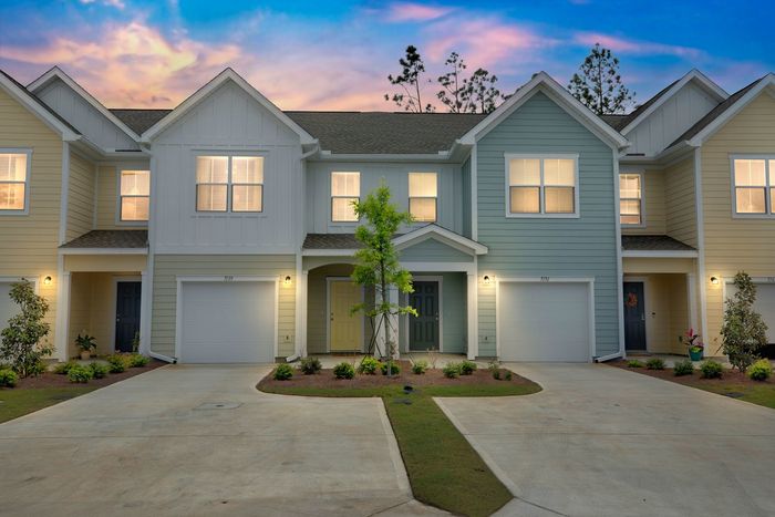Exterior of townhomes at dusk with illuminated windows and outdoor sconce lights