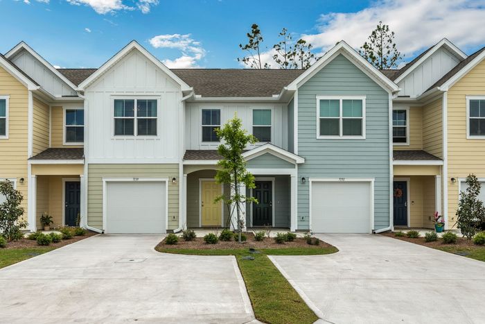 Exterior photo of townhomes in the day time with small tree and shrubbery