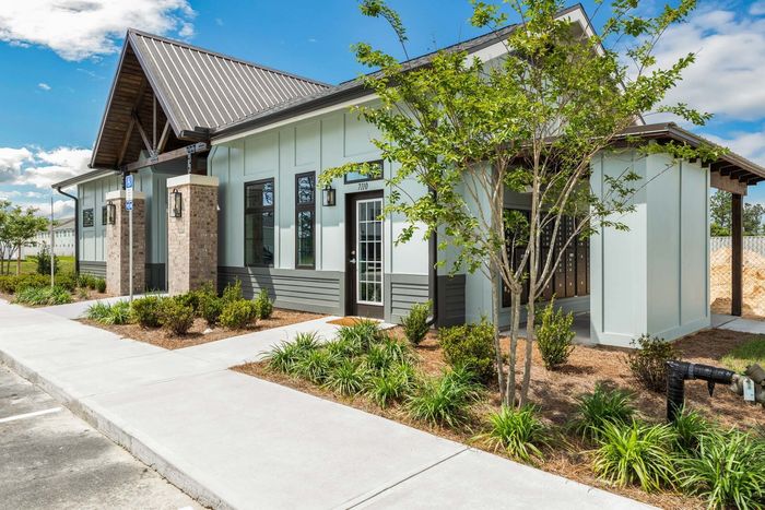 Exterior photo of leasing office in the daytime with shrubbery