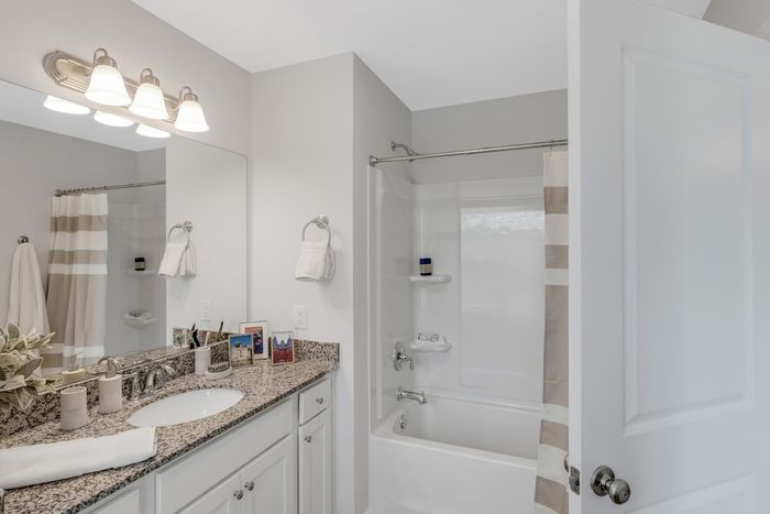 Bathroom with single sink and large mirror above with bathtub