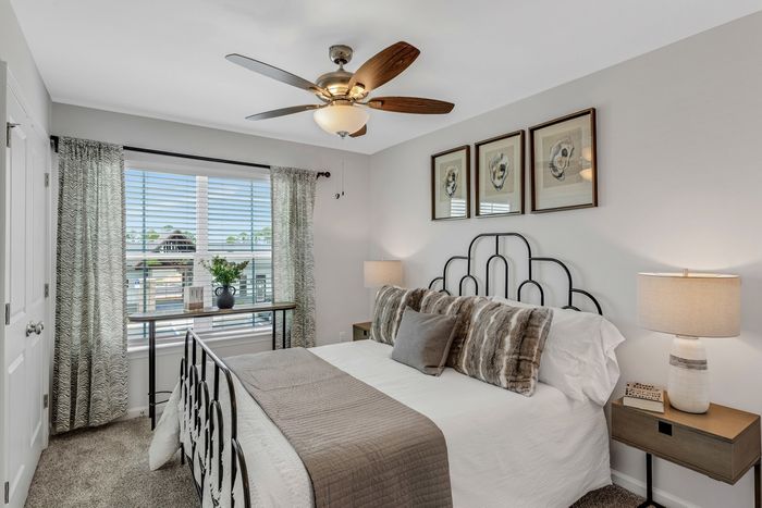 Furnished bedroom with lighted ceiling fan and window
