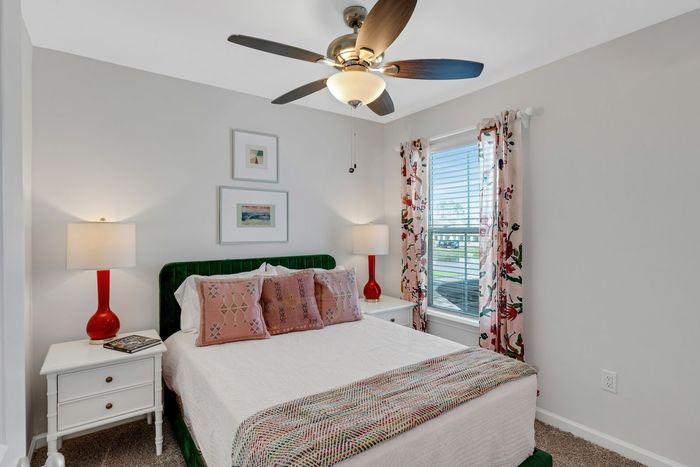 Furnished bedroom with lighted ceiling fan and window