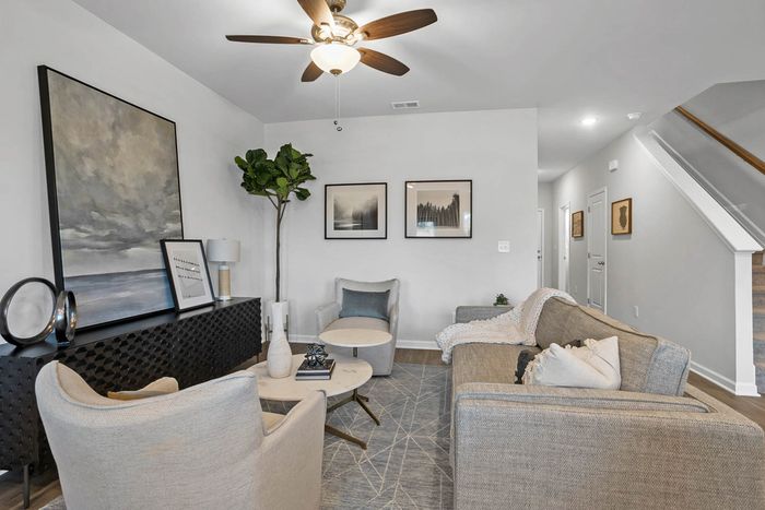 Pet-Friendly Townhomes in Acworth, GA - Covey Homes Hunter Trail - Downstairs Furnished Living Room with Plank Style-Flooring, Staircase to Second Floor, and Ceiling Fan.