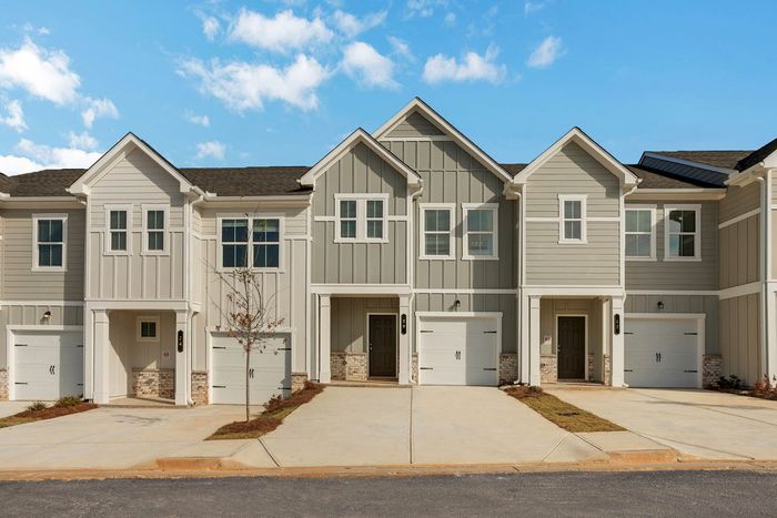 Two-BR Townhomes in Acworth, GA - Covey Homes Hunter Trail - Street View of Exterior Townhomes with Concrete Driveway, Garage, and Maintained Landscaping.