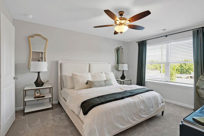 Three-BR Townhomes in Acworth, GA - Covey Homes Hunter Trail - Furnished Bedroom with Plush Carpeting, a Ceiling Fan, and Two Windows.