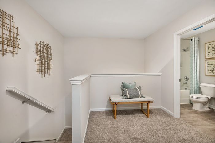 upstairs landing with carpet, bench and neutral wall decorations