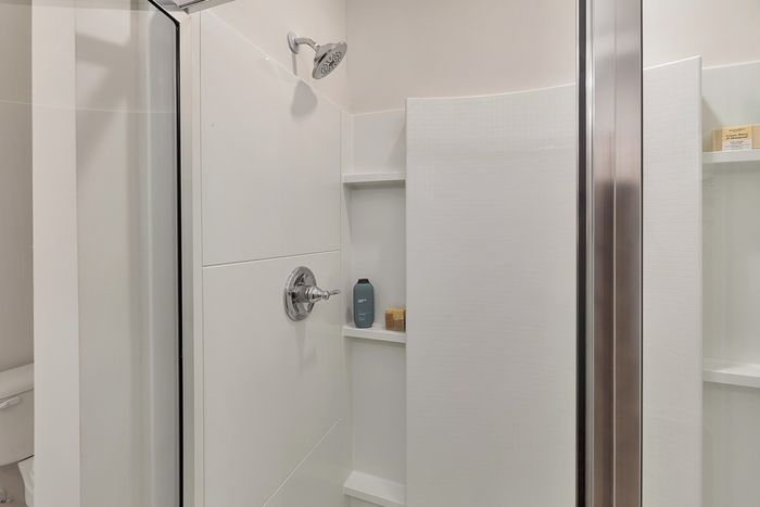 Standing shower with glass door and inset shelving
