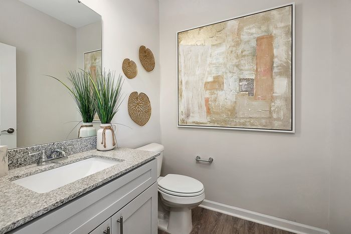 Bathroom with one sink and large mirror and neutral wall art