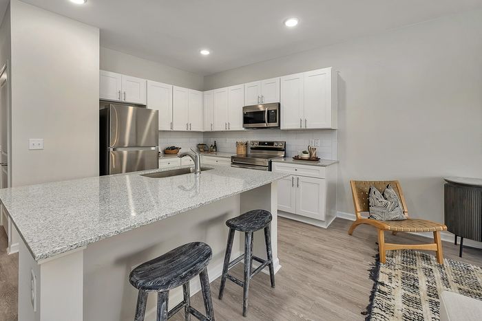 Kitchen with stainless steel apartments and white cabinets with kitchen island and barstools