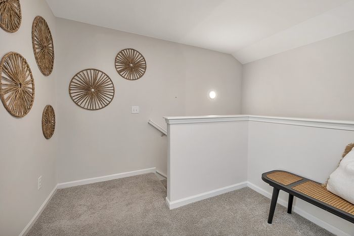 Upstairs landing with carpet, bench, and neautral wall decorations