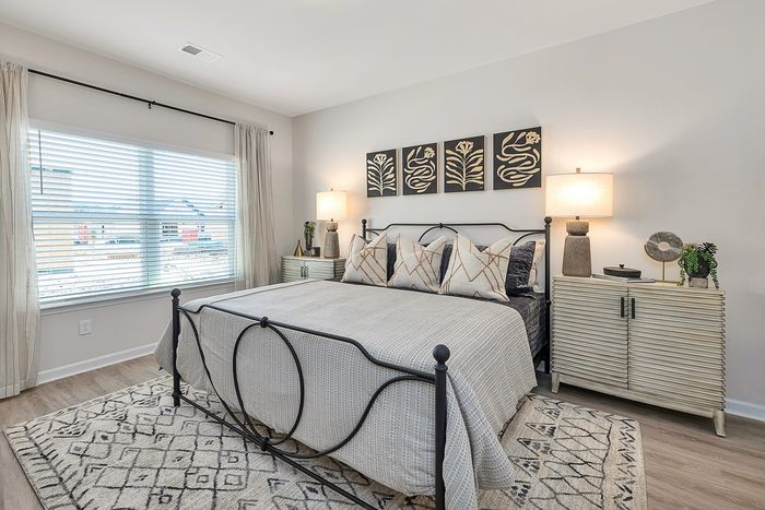 Two-BR Homes in Brunswick, GA - Covey Homes Fox Run - Furnished Bedroom with Wood-Style Flooring and a Wide Window.