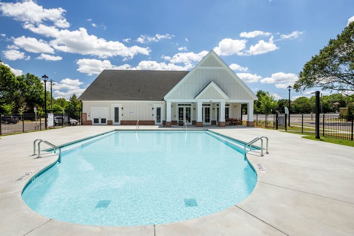 exterior pool with clubhouse building behind it on sunny day