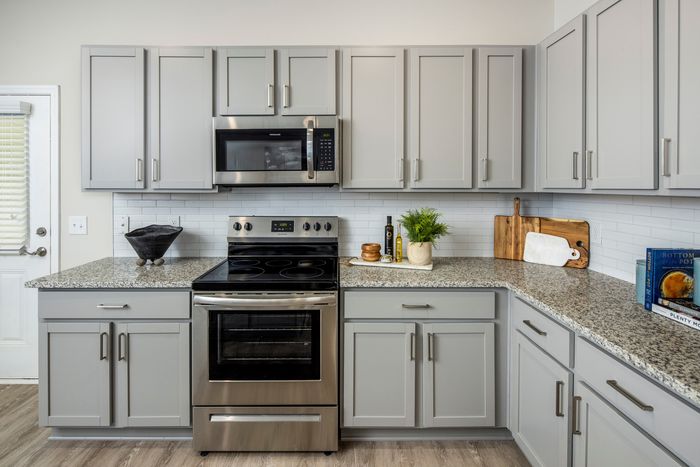 Loganville, GA Homes for Rent - Cottages at Loganville - Kitchen with Granite-Style Counter Spaces, Grey Cabinets, and Stainless-Steel Appliances