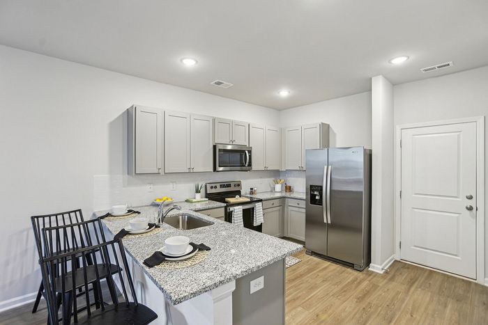 Interior Kitchen with light grey cabinetry, stainless steel appliances and wood style floors