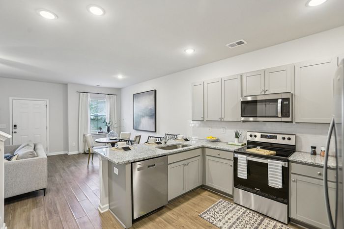 Interior Kitchen with light grey cabinetry, stainless steel appliances and wood style floors
