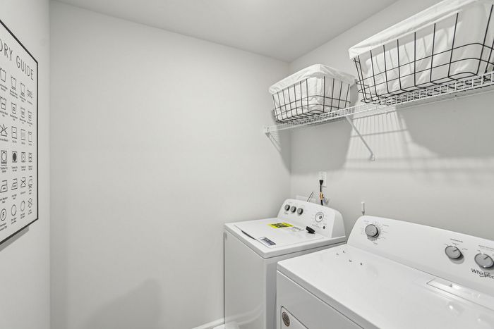 White full size washer and dryer with storage and laundry baskets
