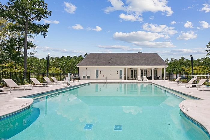 Luxurious apartment community pool area with elegant lounge chairs and lush greenery, perfect for relaxation and leisure.