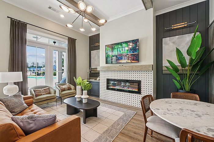 Elegant living room with modern furnishings, cozy fireplace, scenic outdoor view, and vibrant greenery.