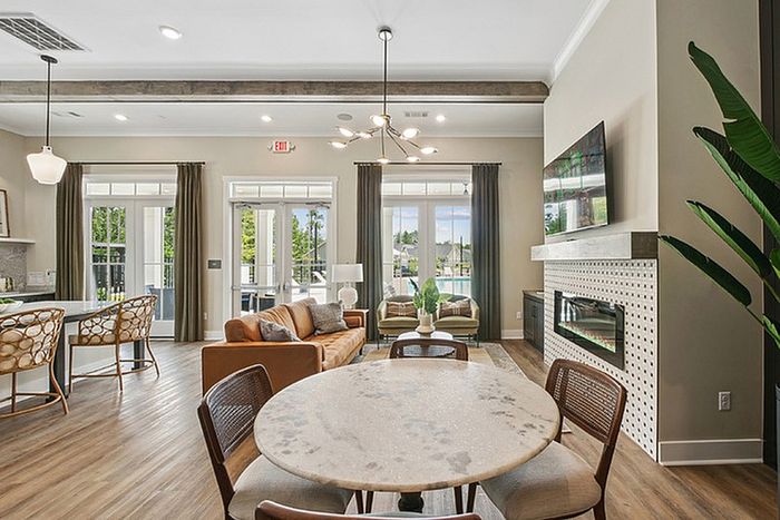 Bright and airy open-plan living area with modern furnishings, elegant dining space, and a stylish fireplace, overlooking a lush outdoor view.