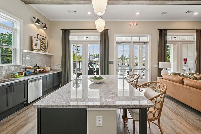 Elegant open-concept kitchen and living area with large island, modern cabinetry, and abundant natural light from patio doors.