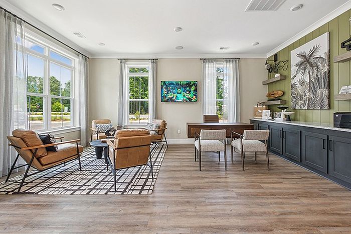 Bright, modern living space with stylish seating, large windows, and elegant wooden flooring; perfect for relaxation and entertainment.