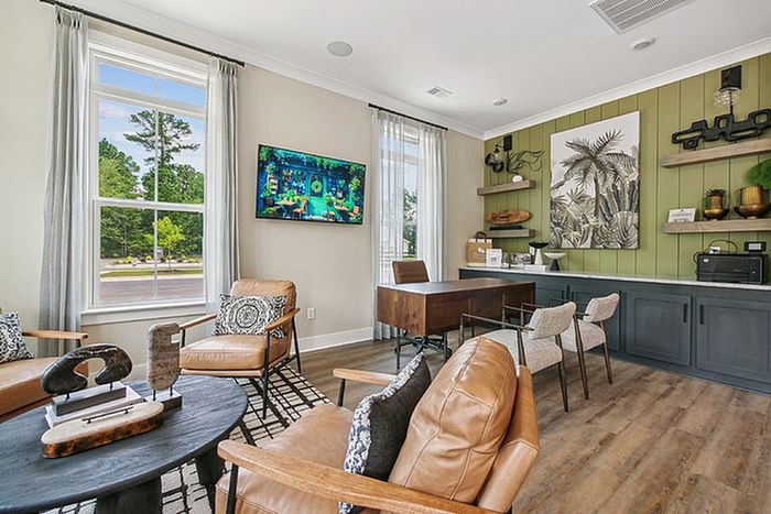 Chic and inviting home office space with modern leather chairs, stylish decor, and a large window providing natural light.