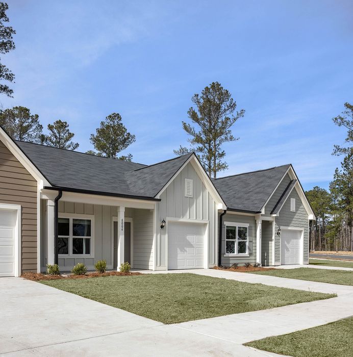 Charming modern homes with pristine facades and spacious driveways set in a serene neighborhood with lush greenery.