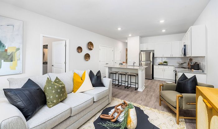 Modern open-concept living room with sleek kitchen, cozy seating, decorative accents, and stylish bar area.