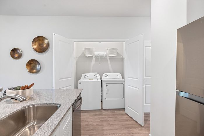 Modern kitchen with sleek countertops and integrated laundry facilities, featuring stylish wall decor and ample storage.