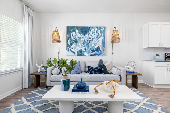 Bright and inviting living space with modern decor, featuring a plush sofa, artistic wall painting, and chic lighting accents.