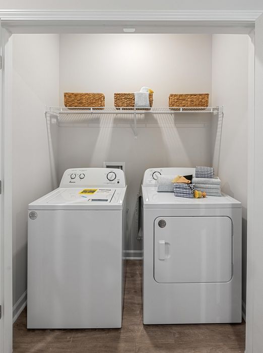 Modern laundry area with sleek washer and dryer set, complemented by wicker storage baskets on a shelf for a stylish organization solution.