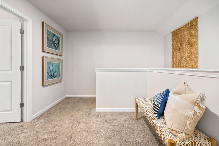 Charming nook with plush carpet and stylish wall art, featuring decorative pillows on a woven bench for a cozy atmosphere.