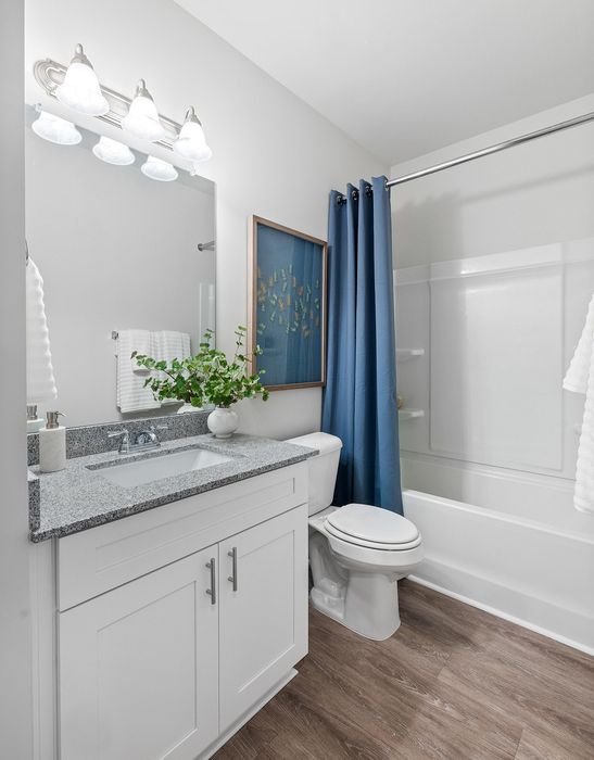 Elegant bathroom with modern fixtures, granite countertop, and stylish blue accents creating a serene spa-like atmosphere.
